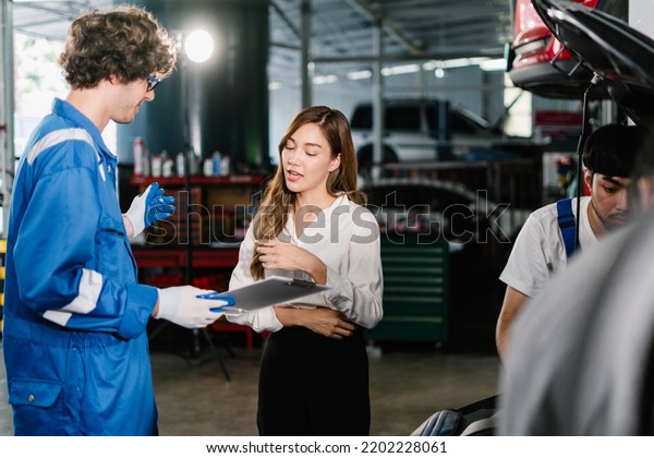 Professional service,\
Auto car repair service center Concept, Mechanic holding a\
clipboard and showing the car checking list and repaired item to\
asian woman customer in the\
garage