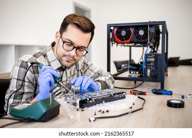 Professional serviceman repairing graphics card and soldering printed circuit board.