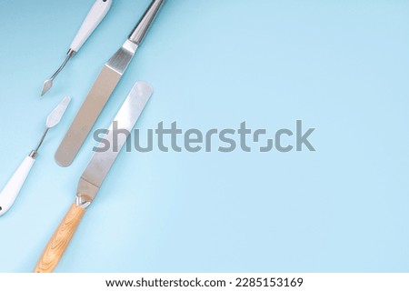 Professional set of spatulas for icing large cakes. starter kit for decorating a cake. Confectioner's tools on a blue background, pastry spatulas. Place for text