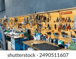 Professional setting of well-organized bicycle repair workshop with workbench and wide array of tools mounted on wooden board, ready for bikes maintenance service