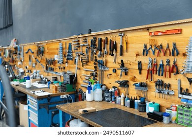 Professional setting of well-organized bicycle repair workshop with workbench and wide array of tools mounted on wooden board, ready for bikes maintenance service - Powered by Shutterstock