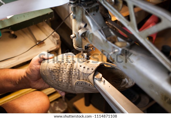 Professional shoemaker heeling footwear on machine in\
workshop. Classic men\'s elegance, stitched shoes at the cobbler.\
adult man working in a shoe factory, sewing the soles of the shoes\
manually. 