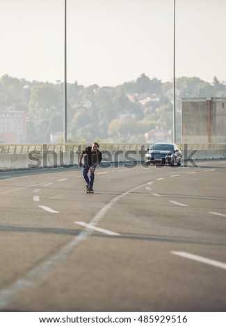 Professional skateboarder riding a skate over a city road bridge, through urban traffic. Free ride skateboards