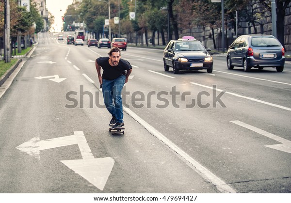 Professional skateboarder\
riding a skateboard slope on the capital city streets, through cars\
and urban traffic