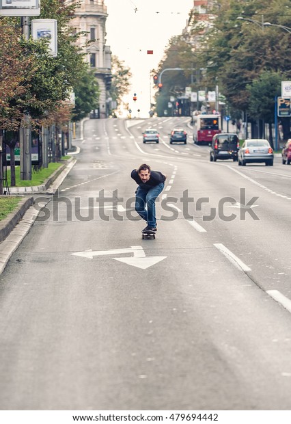 Professional skateboarder\
riding a skateboard slope on the capital city streets, through cars\
and urban traffic