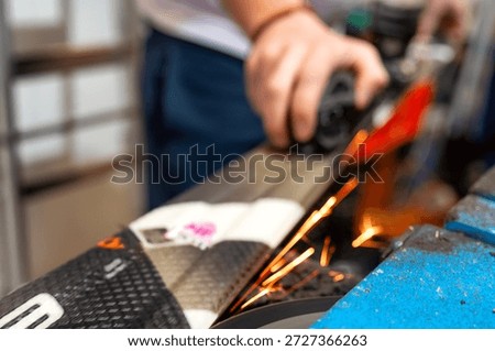 Professional ski servicing process with technician grinding ski edges on a machine. Sparks highlight precision work, equipment maintenance and preparation of skis for alpine skiing and winter season use.