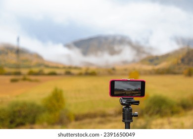 Professional smartphone attached to a tripod, capturing a time-lapse video. The smartphone is focused on the subject, while the surroundings change over time.