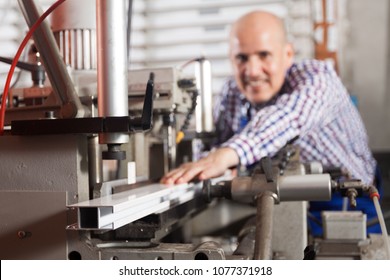 Professional smiling worker toiling on a machine in PVC shop