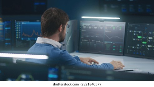 Professional software engineer sits in front of computer with big data server and blockchain network, works in modern monitoring control room with real-time analysis charts. Concept of cyber security.