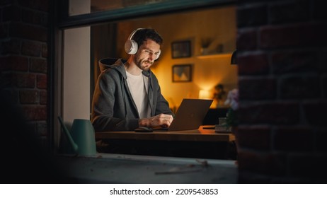 Professional Software Engineer Working From Home Office. Tired IT Specialist Feeling Sleepy And Finising Important Project. Application Development Process. View From Outdoors Into Window.