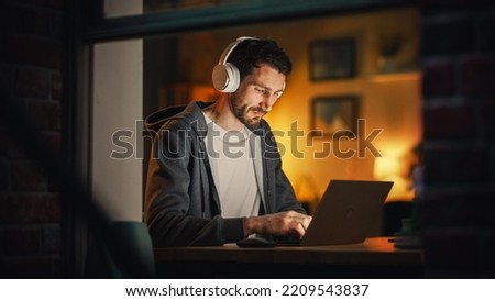 Professional Software Engineer Working From Stylish Home Office. Tired IT Specialist Feeling Sleepy and Finising Important Project. Application Development Process. View From Outdoors into Window.