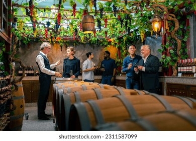 Professional sommelier explaining and recommending wine tasting to group of customers and visitors at wine shop or liquor store. Winery liquor manufacturing industry and winemaker business concept.