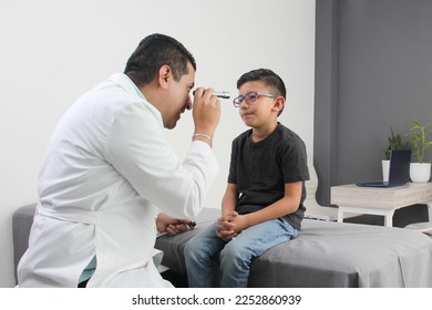 Professional specialist pediatrician doctor and patient 7-year-old Latino brown-haired boy are in consultation to check their eyes, mouth and throat to diagnose any disease in the office - Powered by Shutterstock
