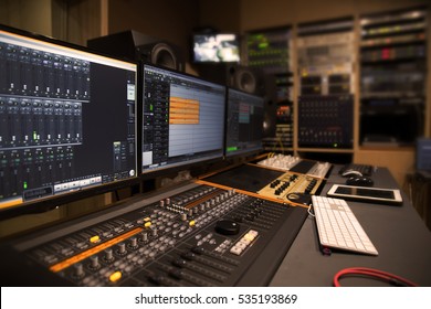 Professional Studio Control Room With Lot Of Studio Equipment In The Background.