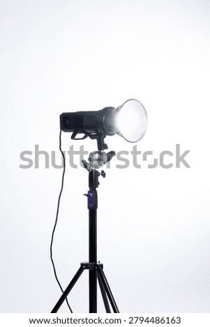Professional studio flash strobe light with reflector on a light stand against a white background.
