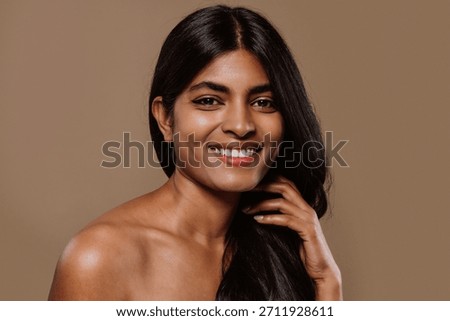 Professional studio portrait capturing young indian woman with long dark hair expressing genuine emotions while posing against neutral brown background