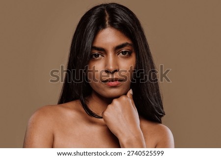 Professional studio portrait capturing young indian woman with long dark hair expressing genuine emotions while posing against neutral brown background