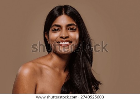 Professional studio portrait capturing young indian woman with long dark hair expressing genuine emotions while posing against neutral brown background