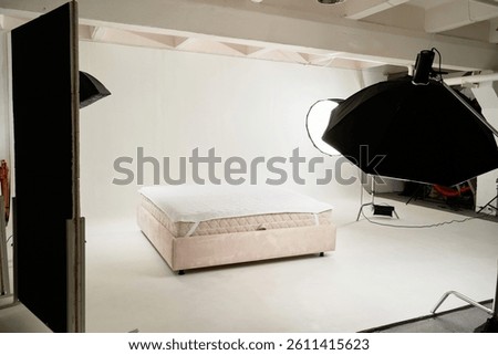 A professional studio setup showcasing a bed prepared for product photography, illuminated by studio lights and equipment, emphasizing luxury and comfort.