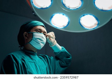 Professional surgeon doctor standing under bright light, using surgical equipment to do surgery at hospital operating room. Surgical team operating surgery patient, healthcare and medical. - Powered by Shutterstock