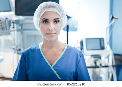 Professional Surgeon. Serious Pleasant Nice Woman Wearing Medical Uniform And Standing In The Operation Room While Working In The Hospital