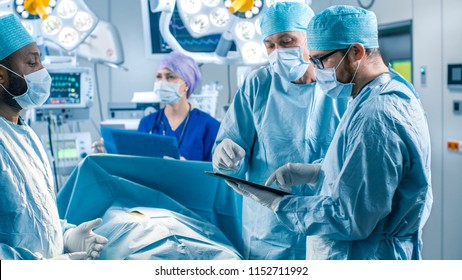 Professional Surgeons and Assistants Talk and Use Digital Tablet Computer During Surgery. They Work in the Modern Hospital Operating Room. - Powered by Shutterstock