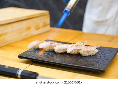 Professional sushi chef hand using gas burner torch to aburi or flame seared sashimi to make perfect sushi with precision and confident. - Powered by Shutterstock