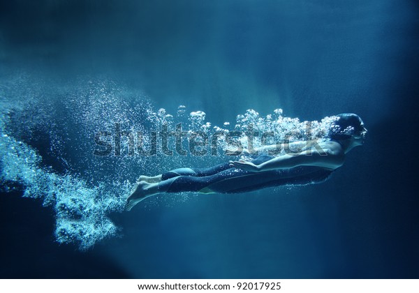 professional swimmer underwater in abyss\
isolated on blue\
background