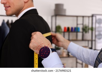 Professional tailor measuring client's back width in atelier, closeup