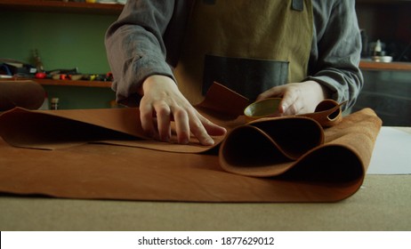 A professional Tanner corrects defects on a roll of genuine leather with a special wax. The process of creating a hand made product.