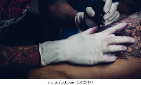 Professional tattoo artist drawing art on body at tattoo shop