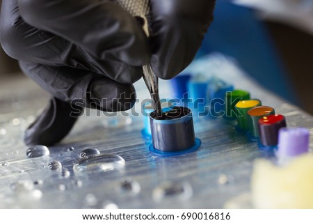 A professional tattoo artist is gaining in the tattoo machine black ink from a jar. tattoo art on body.Makes a tattoo.Professional tattooist working tattooing in studio