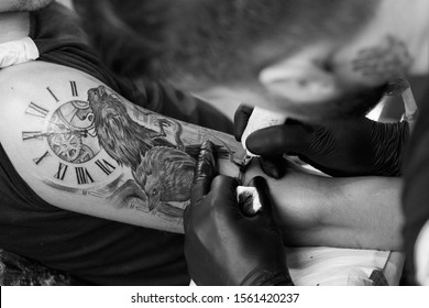 A professional tattoo artist introduces black ink into the skin using a needle from a tattoo machine. tattoo art on body..Professional tattooist working black and white tattooing in studio.