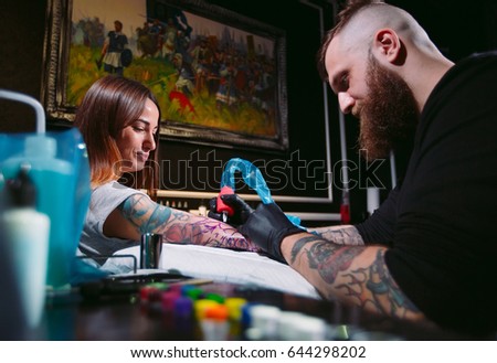 Professional tattoo artist makes a tattoo on a young girl's hand.