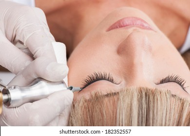 professional tattooist making permanent make up. beautiful girl laying closed eyes