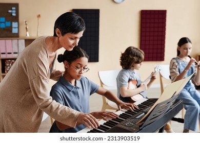 Professional teacher learning children to play musical instruments in music class - Powered by Shutterstock