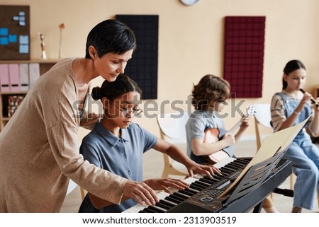 Professional teacher learning children to play musical instruments in music class