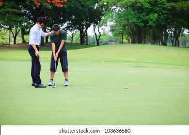 Professional teaching teenager boy to play golf