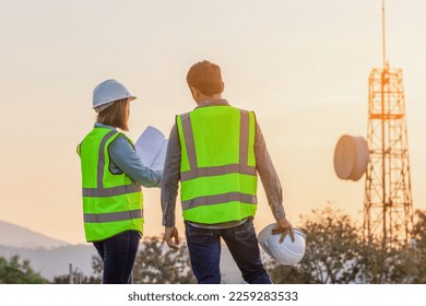 Professional team Engineer managers workers working outdoors with telecommunication antenna and sunset background.
