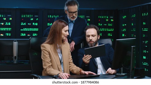 Professional team of programmers sit at desk in office and brainstorm to solve problem. System administrator advises employees.