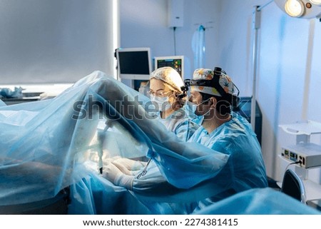 Professional team of surgeons proctologist performing operation using special medical devices in the operating room in hospital. Urgent surgical concept