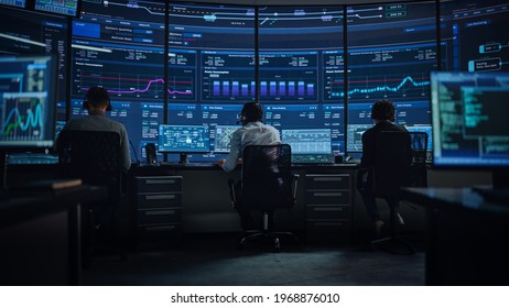 Professional IT Technical Support Specialists And Software Programmer Working On Computers In Monitoring Control Room With Digital Screens With Server Data, Blockchain Network And Surveillance Maps.