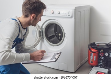 Professional technician checking a washing machine, he is writing on a clipboard