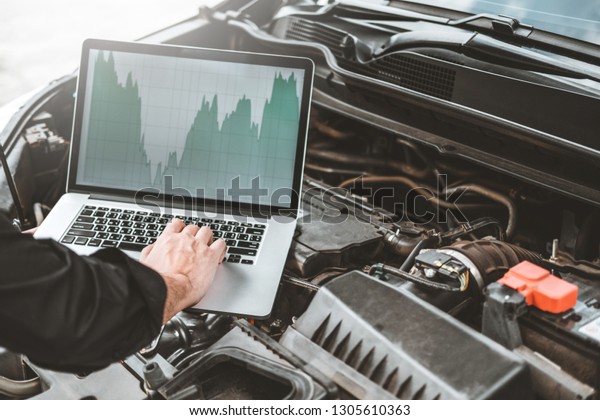 Professional Technician Hands of checking car\
engine repair service using laptop on\
car