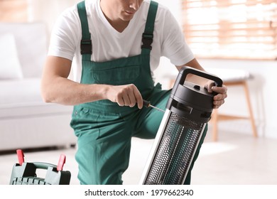 Professional Technician Repairing Electric Patio Heater With Screwdriver Indoors, Closeup