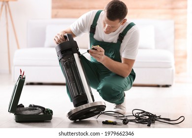 Professional Technician Repairing Electric Patio Heater With Screwdriver Indoors