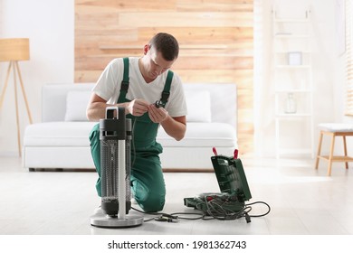 Professional Technician Repairing Electric Patio Heater Indoors