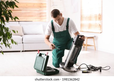 Professional Technician Repairing Electric Patio Heater With Screwdriver Indoors