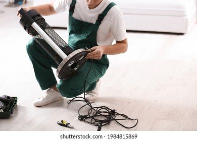 Professional Technician Repairing Electric Patio Heater With Screwdriver Indoors, Closeup