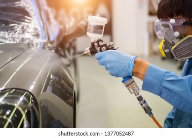 Professional technician Spraying the varnish to the car Ready to wear protective gear.The concept of care scratching paint.Car coating